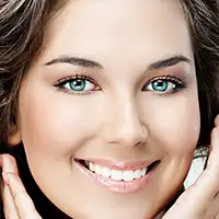 A close-up of a dentist applying bonding material to a tooth.